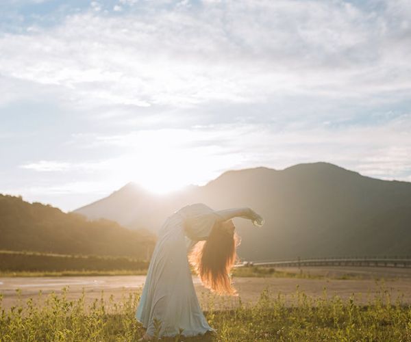 Silhouette of a person in a powerful warrior yoga pose against a rising sun.